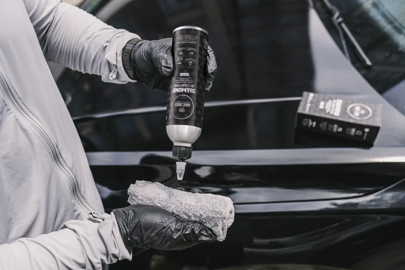 A gloved hand loading Diamond AI onto an applicator cloth.